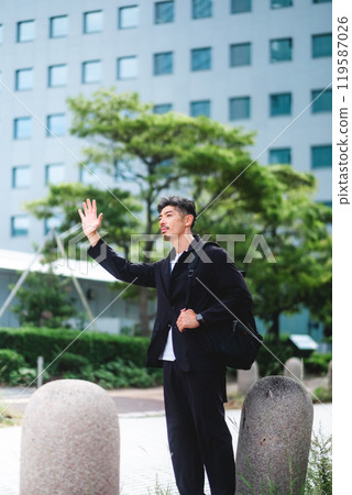 A man stopping a taxi in a business district A man stopping a taxi in a business district 119587026