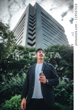A man holding a smartphone among buildings A man holding a smartphone among buildings 119587028