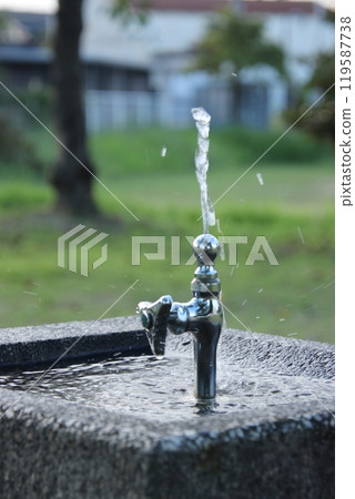 Tap water flowing from a faucet in a park at dusk (September) Tap water flowing from a faucet in a park at dusk (September) 119587738