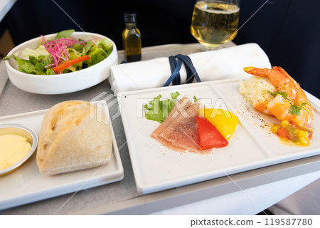 Delicious Business Class in-flight appetizer, salad, prosciutto and shrimp dish and champagne 119587780