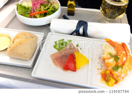 Delicious Business Class in-flight appetizer, salad, prosciutto and shrimp dish and champagne Delicious Business Class in-flight appetizer, salad, prosciutto and shrimp dish and champagne 119587784