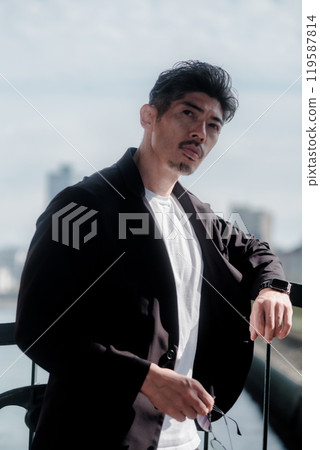 一個穿著套裝的男人站在海邊 119587814