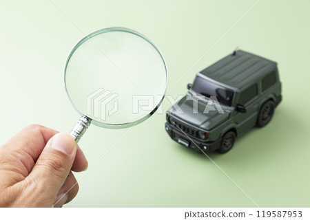 Hands observing a car with a magnifying glass Hands observing a car with a magnifying glass 119587953