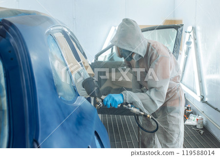 Professional car painter is painting in garage by airbrush. Professional car painter is painting in garage by airbrush. 119588014