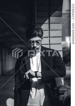 A man wearing glasses looking at his watch during a meeting A man wearing glasses looking at his watch during a meeting 119588121
