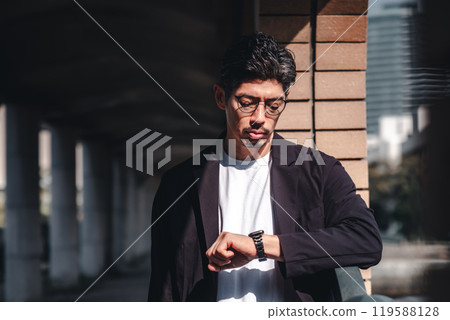 A man wearing glasses looking at his watch during a meeting 119588128