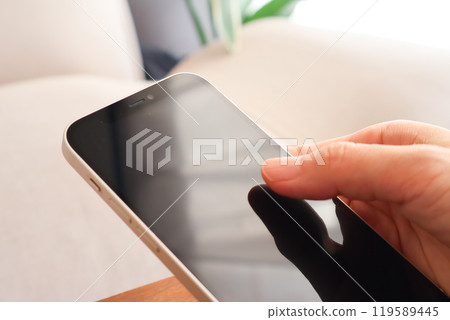 Hand of a woman holding a smartphone Hand of a woman holding a smartphone 119589445
