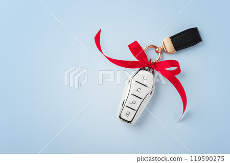 Car key with red bow ribbon on blue background, top view Car key with red bow ribbon on blue background, top view 119590275