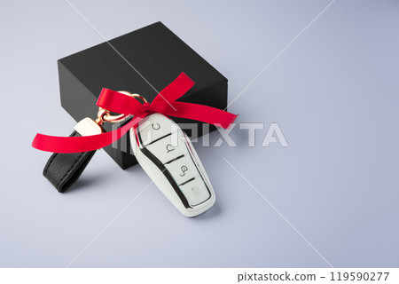Car key with red bow ribbon and black gift box on purple background Car key with red bow ribbon and black gift box on purple background 119590277