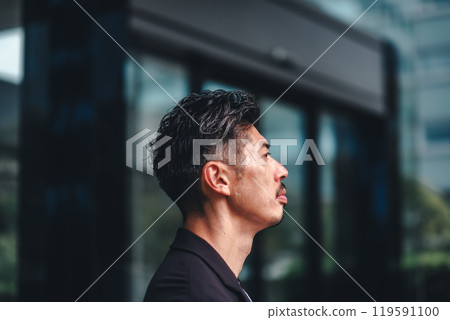 A man in a suit standing in front of a building 119591100