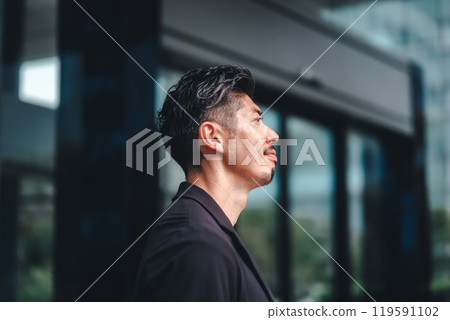 一個穿著西裝的男人站在大樓前 一個穿著西裝的男人站在大樓前 119591102