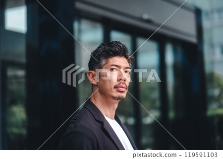 一個穿著西裝的男人站在大樓前 119591103