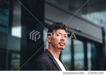 一個穿著西裝的男人站在大樓前 一個穿著西裝的男人站在大樓前 119591104