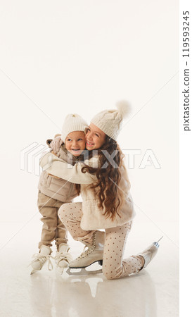 Big sister comforts her little brother during moment of rest on ice, quiet sibling moment amidst fun against white studio background. 119593245