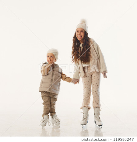 Laughing and playful, siblings share sweet hug during their Christmas ice skating session against white studio background. Laughing and playful, siblings share sweet hug during their Christmas ice skating session against white studio background. 119593247