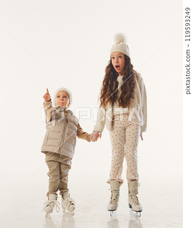 Kids spot something exciting as they continue their skating fun, filled with wonder and holiday spirit against white studio background. 119593249
