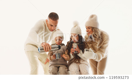 Dad pours hot tea while kids eagerly hold their mugs, savoring sweet family moment on ice against white studio background. 119593273