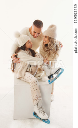 Family shares cozy moment, all smiles as they prepare for next round of winter skating fun against white studio background. Family shares cozy moment, all smiles as they prepare for next round of winter skating fun against white studio background. 119593289