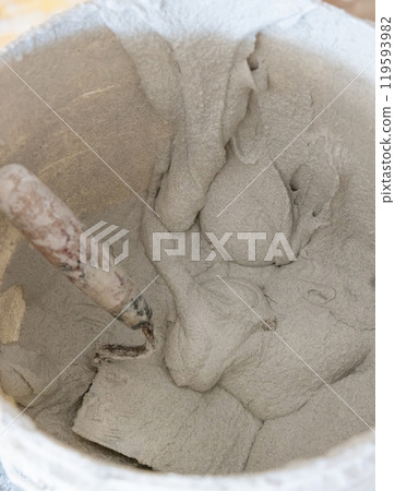 Bucket with cement or plaster with trowel inside, covered in cement residue, top view Bucket with cement or plaster with trowel inside, covered in cement residue, top view 119593982