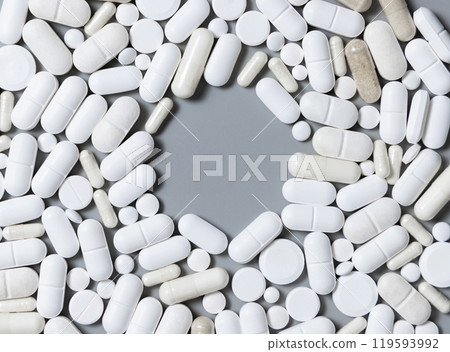 White medical capsules and pills with copy space in the middle on grey top view White medical capsules and pills with copy space in the middle on grey top view 119593992