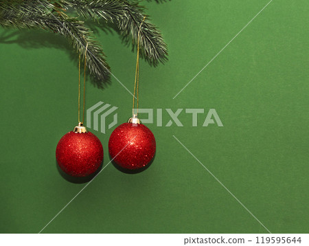 New Year's red shiny balls hanging on a fir branch on a dark green background with space for text 119595644