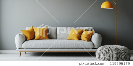 Modern living room with light gray sofa and yellow accent pillows illuminated by floor lamp 119596179