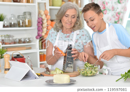 A young boy with his grandmother cooking in the kitchen 119597081