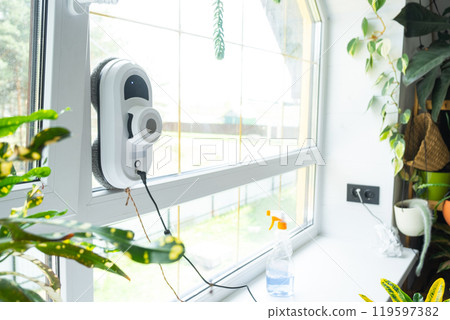 A window cleaner robot cleans windows in a house from the inside. Cleaning assistant, safe window cleaning, remote control A window cleaner robot cleans windows in a house from the inside. Cleaning assistant, safe window cleaning, remote control 119597382