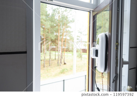 A window cleaner robot cleans windows in a house from the outside. Cleaning assistant, safe window cleaning, remote control A window cleaner robot cleans windows in a house from the outside. Cleaning assistant, safe window cleaning, remote control 119597392