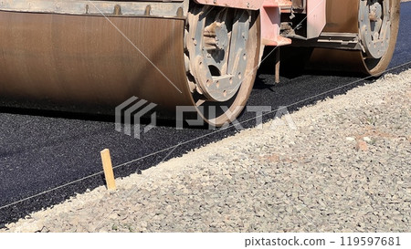 Asphalt paving roller. Road roller laying fresh asphalt, working on the new road construction site Asphalt paving roller. Road roller laying fresh asphalt, working on the new road construction site 119597681
