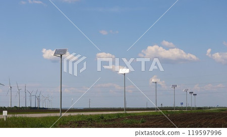 solar panels along highway with wind turbines in background, green energy of solar and wind power, renewable resources of planet earth, roadside panels and wind generators in fields solar panels along highway with wind turbines in background, green energy of solar and wind power, renewable resources of planet earth, roadside panels and wind generators in fields 119597996