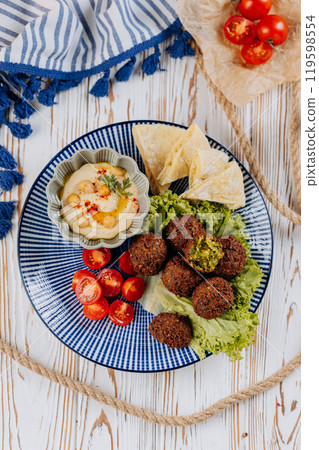 Falafel plate with hummus, cherry tomatoes, lettuce, and pita chips, perfect Mediterranean meal 119598554