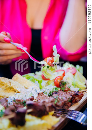 Dining experience with fresh salad, grilled skewers, pita, and fries, perfect Mediterranean meal 119598562