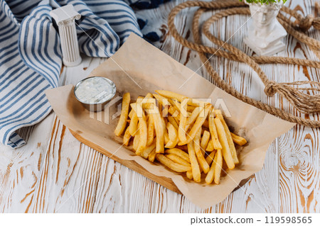 Golden French fries with a side of creamy dip, perfect for snack lovers 119598565