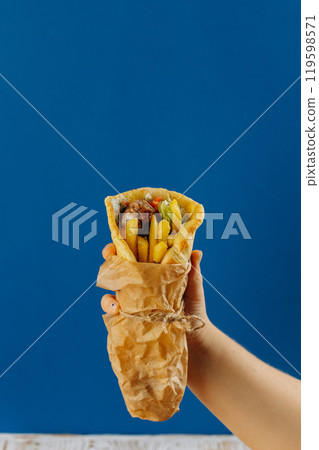 Fresh gyro wrap with fries, vegetables, and tzatziki sauce, perfect for a quick Mediterranean bite Fresh gyro wrap with fries, vegetables, and tzatziki sauce, perfect for a quick Mediterranean bite 119598571