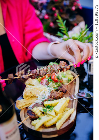 Grilled skewers with crinkle fries, pita, and salad, delicious outdoor dining experience 119598575