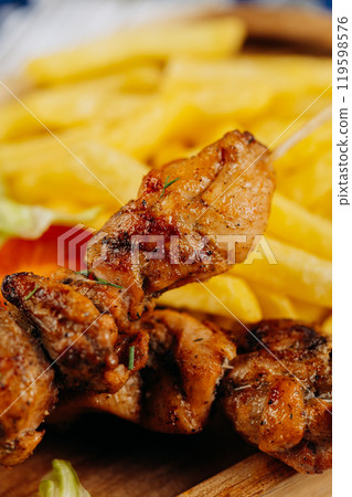 Close-up of juicy grilled chicken skewers served with crispy fries, perfect for lunch or dinner Close-up of juicy grilled chicken skewers served with crispy fries, perfect for lunch or dinner 119598576