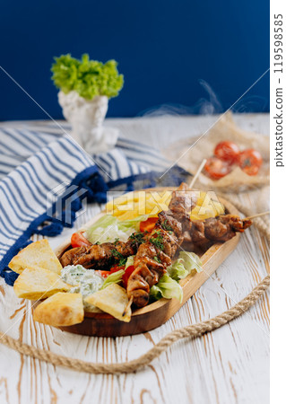 Grilled chicken skewers with vegetables, fries, and pita bread. Perfect Mediterranean dish Grilled chicken skewers with vegetables, fries, and pita bread. Perfect Mediterranean dish 119598585