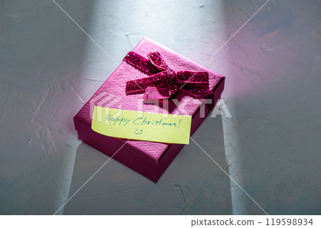 A ray of light illuminates the Happy Christmas note on the gift box. 119598934