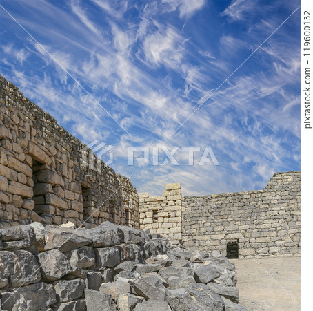 Ruins of Azraq Castle (Qasr al-Azraq) is a crusader castle (300AD),  central-eastern Jordan, 100 km east of Amman, Jordan. Against the background of a beautiful sky with clouds 119600132