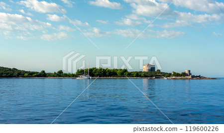 Yacht in the sea against the backdrop of rocks with dense vegetation and an abandoned fort Yacht in the sea against the backdrop of rocks with dense vegetation and an abandoned fort 119600226
