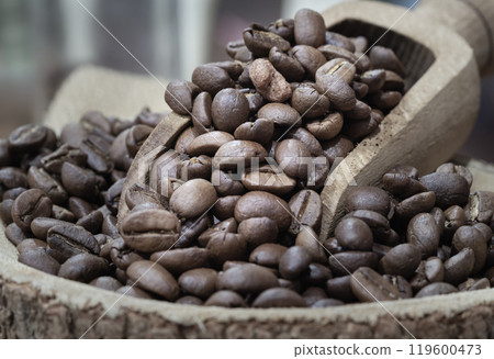 Coffee beans in wooden scoop on round wooden bowl. Coffee beans in wooden scoop on round wooden bowl. 119600473