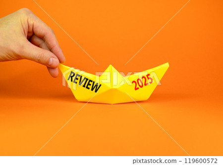 Planning review 2025 new year symbol. Concept words Review 2025 on beautiful yellow paper boat. Beautiful orange paper background. Businessmen hand. Business review 2025 new year concept. Copy space. 119600572