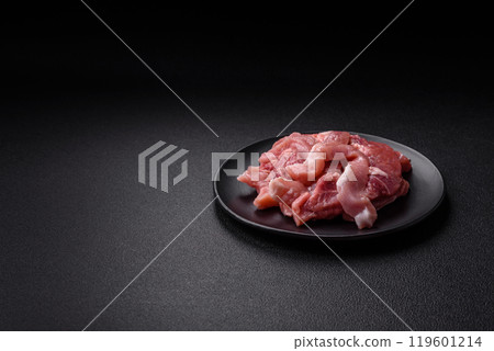 A pieces of raw fresh pork on a wooden cutting board with spices and herbs A pieces of raw fresh pork on a wooden cutting board with spices and herbs 119601214