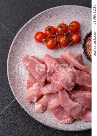 A pieces of raw fresh pork on a wooden cutting board with spices and herbs A pieces of raw fresh pork on a wooden cutting board with spices and herbs 119601230