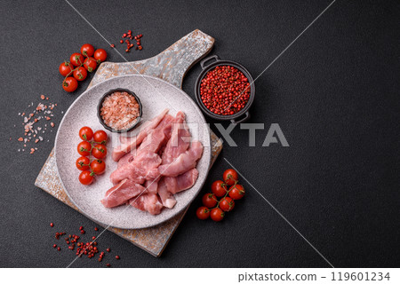 A pieces of raw fresh pork on a wooden cutting board with spices and herbs 119601234