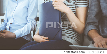 Group of casual dressed business people sitting in a line while waiting for a job interview. Unemployment as the effects of the COVID crisis 119601341