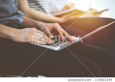 Group of casual dressed business people working at meeting or conference in sunny office, close-up of hands. Businessman using tablet computer Group of casual dressed business people working at meeting or conference in sunny office, close-up of hands. Businessman using tablet computer 119601344