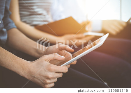 Group of casual dressed business people working at meeting or conference in sunny office, close-up of hands. Businessman using tablet computer 119601346