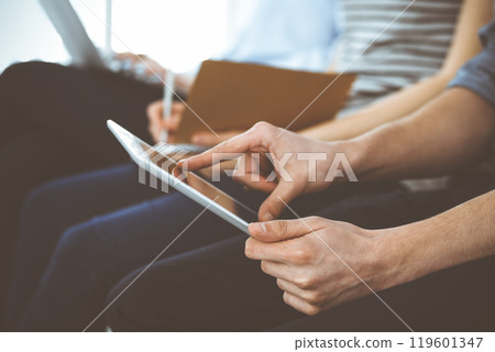 Group of casual dressed business people working at meeting or conference, close-up of hands. Businessman using tablet computer. Teamwork or coaching concept Group of casual dressed business people working at meeting or conference, close-up of hands. Businessman using tablet computer. Teamwork or coaching concept 119601347